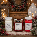 Load image into Gallery viewer, Three hand-poured jar candles from Southern Charm Farmhouse are displayed on a rustic wooden surface with holiday decorations. The left candle is 'Christmas Cookie' in a creamy off-white wax, the center candle is 'Fireside Magic' in a red wax with a silver lid, and the right candle is 'Home & the Holidays' in a bright red wax.