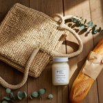 Load image into Gallery viewer, Woven bag, 16 oz Mason Jar French Market Candle, and loaf of bread on a wooden surface with eucalyptus leaves. Southern Charm Farmhouse