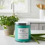Load image into Gallery viewer, Teal 2 Wick candle labeled 'Green Clover & Aloe' on a kitchen counter with a plant and aloe vera leaves.