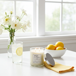 Load image into Gallery viewer, 2 Wick Lemon Verbena hand poured Candle with a lemon vanilla scent on a table with lemons, a glass of water, and flowers. Southern Charm Farmhouse.