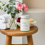 Load image into Gallery viewer, 16 oz Mason jar hand poured Love Spell Candle on a wooden table with flowers and towels in the background. Southern Charm Farmhouse