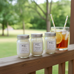 Load image into Gallery viewer, Three hand poured 4 oz. jars of candles on a wooden ledge with a glass of iced tea with lemon slices in the background. Southern Charm Farmhouse.