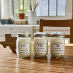 Load image into Gallery viewer, Three 4 oz jars of hand poured candles with labels on a wooden surface, with a blurred indoor background. Southern Charm Farmhouse