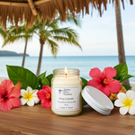 Load image into Gallery viewer, Pina Colada Candle lit in 16 oz Mason jar candle on a wooden surface with tropical flowers and a beach background. Southern Charm Farmhouse.