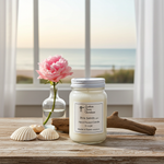Load image into Gallery viewer, 16 oz Mason Jar of 'Pink Sands' candle with a pink flower and seashells on a wooden surface with a window view. Southern Charm Farmhouse
