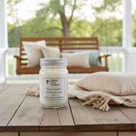 Load image into Gallery viewer, 16 oz mason jar of Satin & Suede hand poured candle on a wooden table with a blurred outdoor background. Southern Charm Farmhouse.