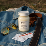 Load image into Gallery viewer, 16 oz Mason Jar of hand poured Scarlet Sunset candle, sunglasses, and tickets on a denim jacket outdoors. Southern Charm Farmhouse.