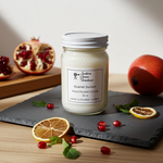 Load image into Gallery viewer, 16 oz mason Jar of hand poured Scarlet Sunset candle with pomegranate and orange slices on a slate surface. Southern Charm Farmhouse.