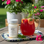 Load image into Gallery viewer, Hand poured Scarlet Sunset Candle and pitcher of red drink on a tray with flowers in the background. Southern Charm Farmhouse.