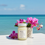 Load image into Gallery viewer, 16 oz Mason jar hand poured Sea Salt & Orchid Candle with flowers on a table by the ocean. Southern Charm Farmhouse.