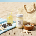 Load image into Gallery viewer, 16 oz Hand poured Mason jar Sun and sand candle with a drink, sunglasses, and beach accessories on a wooden surface with sand background. Southern Charm Farmhouse.