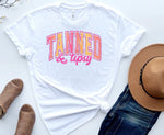 Load image into Gallery viewer, A white t-shirt with the text 'Tanned & Tipsy' printed in pink and orange letters, accompanied by summer-themed items like a hat and sunglasses. Southern Charm Farmhouse.