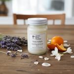 Load image into Gallery viewer, 16 oz hand poured mason Jar of candle labeled 'Texas Twilight' with lavender, oranges, and flowers on a wooden surface. Southern Charm Farmhouse.