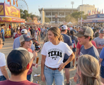 Load image into Gallery viewer, Woman in a 'Texas Girl' shirt standing in a crowd at a fair with a Ferris wheel in the background. Southern Charm Farmhouse.