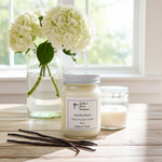 Load image into Gallery viewer, Vanilla Bean Candle in a 16 oz Mason jar with vanilla beans and flowers on a wooden surface. Southern Charm Farmhouse.