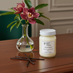 Load image into Gallery viewer, 16 oz Mason Jar of 'Vanilla Passion' candle with a vase of flowers and vanilla beans on a wooden surface. Southern Charm Farmhouse.