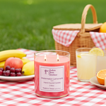 Load image into Gallery viewer, 2 wick hand poured Pink candle labeled 'Watermelon Lemonade' on a picnic table with fruits and drinks. Southern Charm Farmhouse.