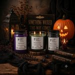 Load image into Gallery viewer, Three hand-poured candles in glass jars with black lids are arranged on a rustic wooden surface with Halloween decorations, including a lit lantern, a carved pumpkin, black spiderwebs, old books, and a sign reading 'SOMETHING WICKED THIS WAY COMES'. The candles are labeled 'Southern Charm Farmhouse