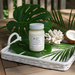 Load image into Gallery viewer, 16 oz Mason Jar of Cheirosa 62 candle on a leaf with a white tray, coconut, and coral on a wooden surface. Southern Charm Farmhouse.