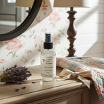 Load image into Gallery viewer, Linen 4 oz spray bottle on a wooden surface with lavender and a lamp in the background. Southern Charm Farmhouse.