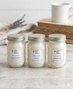 Load image into Gallery viewer, Three mini 4 oz hand poured jars of candles with labels on a wooden surface, with a cup and lavender in the background. Southern Charm Farmhouse.