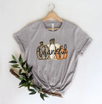 Load image into Gallery viewer, A gray unisex long-sleeve t-shirt with a graphic of three pumpkins and the word 'THANKFUL' on the front, displayed on a hanger. Southern Charm Farmhouse.