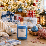 Load image into Gallery viewer, A lit blue hand poured candle labeled 'Jack Frost' sits on a wooden table surrounded by holiday decorations, wrapped gift boxes, ornaments, a knitted blanket, and a Christmas tree in the background.  Southern Charm Farmhouse.
