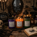 Load image into Gallery viewer, Three lit hand-poured candles in glass jars with black lids are displayed on a rustic wooden table in a dark, gothic-themed room. The candles have purple, orange, and green wax, with labels reading 'Witching Hour', 'Pumpkin Hollow', and 'Witches Brew'. Southern Charm Farmhouse
