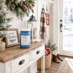 Load image into Gallery viewer, A styled holiday entryway with a white console table holding a blue hand poured Jack Frost candle jar, a framed Merry Christmas sign, a lantern, a plaid scarf, and baskets near a glass door. Southern Charm Farmhouse.
