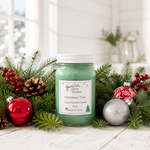 Load image into Gallery viewer, A green hand-poured candle in a clear glass jar with a white lid and a white label reading 'Christmas Tree' by Southern Charm Farmhouse, styled on a white wooden surface with pine branches, red berries, pinecones, and red and silver ornaments.
