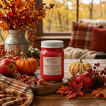 Load image into Gallery viewer, A red 16 oz mason jar candle labeled 'Apple Berry Harvest' sits on a wooden table surrounded by fall decor, including apples, pumpkins, leaves, berries, and a plaid cloth, with a softly blurred indoor outdoor background. Southern Charm Farmhouse.
