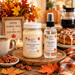 Load image into Gallery viewer, Two Southern Charm Farmhouse Handmade fragrance products displayed on a wooden tray in an autumn-themed setting: a hand-poured candle labeled Caramel Cappuccino Brulee and a room spray bottle labeled Vanilla Maple Pecan. The scene includes fall leaves, a mug, pecans, a sign, and baked goods in the background.
