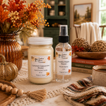 Load image into Gallery viewer, Two Southern Charm Farmhouse home fragrance products displayed on a table runner in a cozy autumn-themed setting: a jar candle labeled Caramel Cappuccino Brulee and a room spray bottle labeled Vanilla Maple Pecan.
