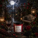 Load image into Gallery viewer, A red scented hand poured candle in a glass jar with a black lid sits on a stone surface in a gothic garden scene at night. The label reads 'Bite Me' and 'Hand Poured in Texas. Southern Charm Farmhouse.
