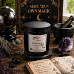 Load image into Gallery viewer, A black jar hand poured candle labeled 'Black Magic' by Southern Charm Farmhouse, styled on a wooden table with a crystal ball, amethyst cluster, occult book, and a sign reading 'MAKE YOUR OWN MAGIC'.
