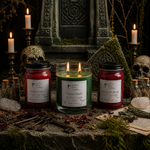 Load image into Gallery viewer, Three hand poured candles in glass jars from Southern Charm Farmhouse are arranged on a stone surface with gothic props including skull candles, mossy fabric, keys, dried petals, and old papers.
