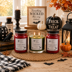 Load image into Gallery viewer, Three Halloween-themed scented hand poured candles displayed on a woven placemat in a cozy fall table setting. The set includes a red jar candle labeled 'Dragon's Blood', a green 2 wick jar candle labeled 'Poison Apple', and another red jar candle labeled 'Vampire's Blood'. Southern Charm Farmhouse
