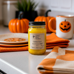 Load image into Gallery viewer, Yellow 16 oz mason jar hand poured candle labeled 'Candy Corn' on a kitchen counter with pumpkins and a Halloween-themed mug. Southern Charm Farmhouse
