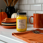 Load image into Gallery viewer, 16 oz mason Jar of 'Candy Corn' hand poured candle on a kitchen counter with a mug and pumpkins in the background. Southern Charm Farmhouse
