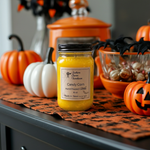 Load image into Gallery viewer, Halloween-themed hand poured candle with candy corn scent on a decorative table with pumpkins and spider webs. Southern Charm Farmhouse
