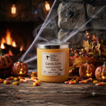 Load image into Gallery viewer, A Halloween-themed candle in a glass jar with a silver lid, labeled ' Candy Corn Hand Poured Candle'. The candle is styled on a rustic wooden table with scattered candy corn, jack-o'-lanterns, autumn leaves, and a blurred fireplace background with a spider decoration. Southern Charm Farmhouse.
