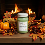 Load image into Gallery viewer, 16 oz Mason jar Green hand poured candle jar with label named Cedar &amp; Autumn Leaves on a wooden surface with autumn decorations and a fireplace in the background.  Southern Charm Farmhouse.
