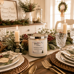 Load image into Gallery viewer, A hand-poured candle in a clear glass jar with a silver lid sits on a decorated dining table. The candle label reads 'Christmas Cheer. Southern Charm Farmhouse.
