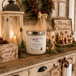 Load image into Gallery viewer, A jar hand poured candle labeled 'Christmas Cheer' by Southern Charm Farmhouse. sits on a rustic wooden mantel decorated for Christmas with a lantern, small house lights, a wreath, and a 'Merry Christmas' sign.
