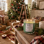 Load image into Gallery viewer, A lit green hand poured candle in a clear glass jar sits on a wooden table in a cozy, decorated living room. The label reads ' Christmas Tree' . Southern Charm Farmhouse.
