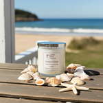 Load image into Gallery viewer, 2 wick hand poured Candle labeled 'Coastal Cottage' on a wooden surface with seashells and a beach view. Southern Charm Farmhouse.
