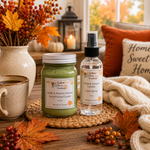 Load image into Gallery viewer, Two fall-themed scented products from Southern Charm Farmhouse are displayed on a woven placemat on a wooden table. The products are a hand-pounded candle in a green jar and a linen spray in a clear bottle, surrounded by autumn props like orange leaves, a mug, and a cozy throw blanket.
