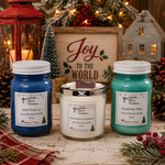 Load image into Gallery viewer, Three hand-poured holiday scented candles in 16 oz mason jars with white lids are displayed on a rustic wooden surface. The left jar is blue with a white label reading 'Jack Frost'; the center jar is clear with white wax and a silver lid, labeled 'Marshmallow Wonderland'; the right jar is teal with a white label reading 'Christmas Tree'. Southern Charm Farmhouse.
