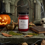 Load image into Gallery viewer, Red hand poured candle labeled 'Dragon's Blood' on a stone surface with Halloween decorations. Southern Charm Farmhouse.
