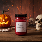 Load image into Gallery viewer, Red hand poured candle labeled 'Dragons Blood' with Halloween decorations like a pumpkin and skulls in the background. Southern Charm Farmhouse.
